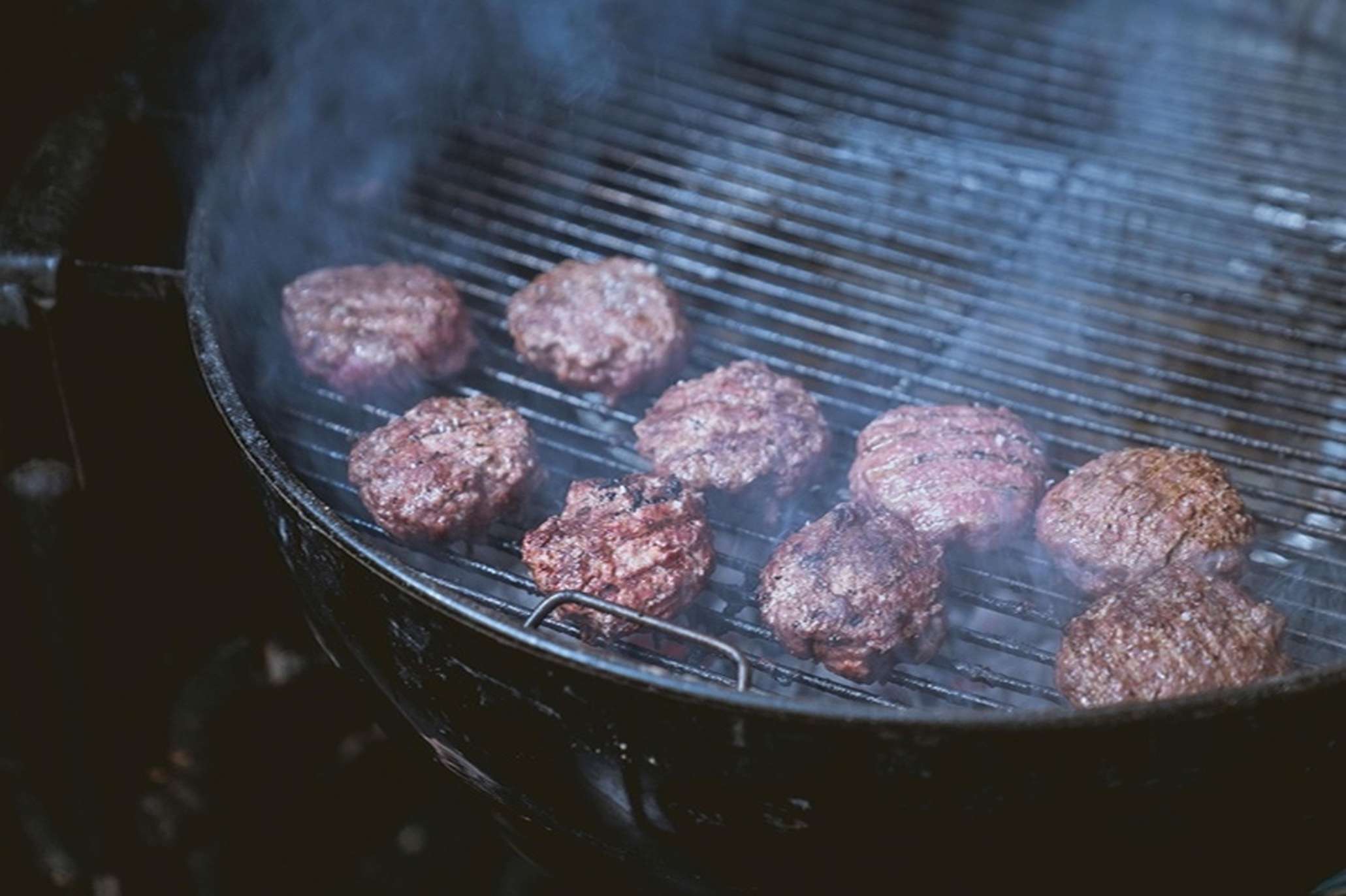 Hamburgers gegrild op een kamado barbecue voor een perfecte rooksmaak